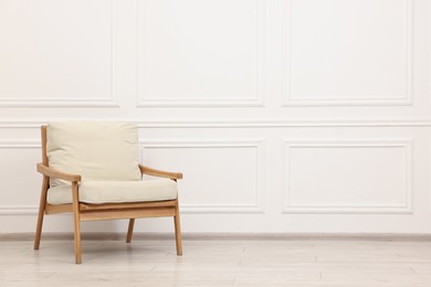 Photo of Comfortable soft armchair near white wall, space for text