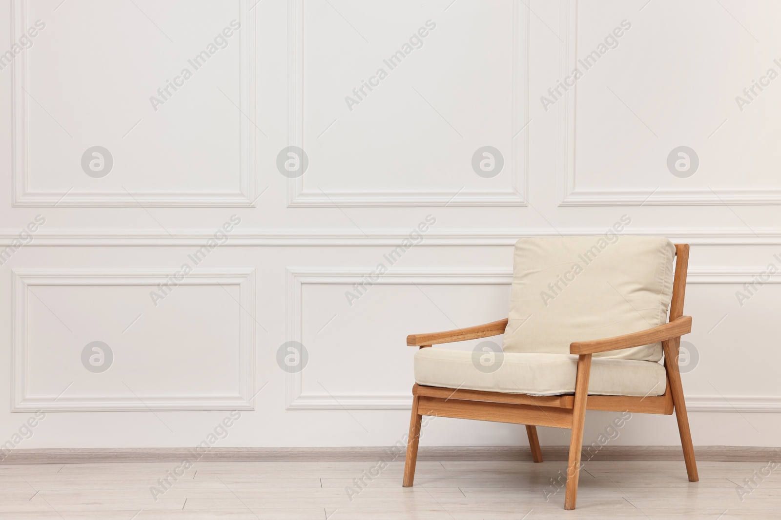 Photo of Comfortable soft armchair near white wall, space for text