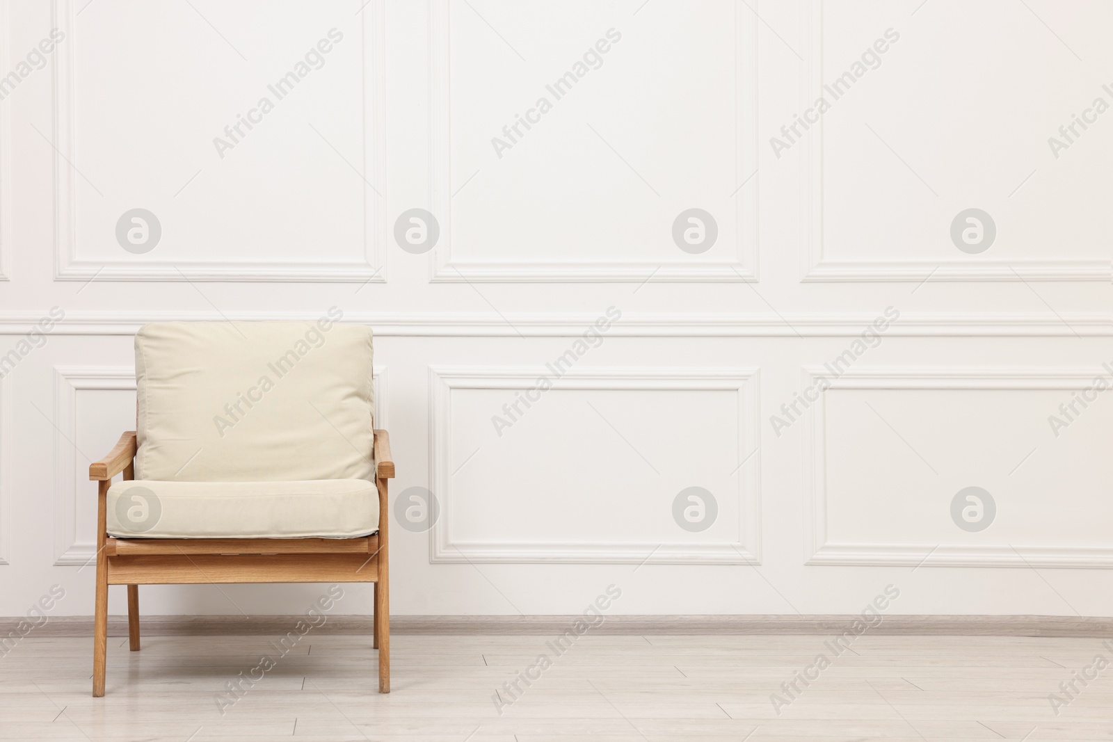 Photo of Comfortable soft armchair near white wall, space for text