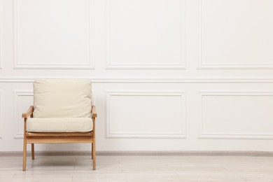 Comfortable soft armchair near white wall, space for text