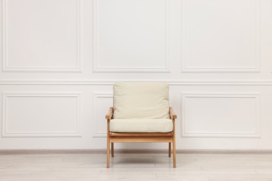 Photo of One comfortable soft armchair near white wall