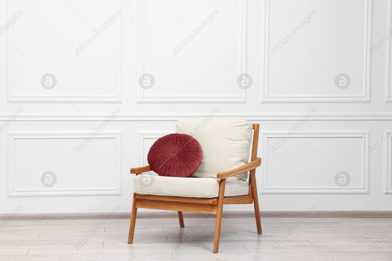 Photo of Comfortable soft armchair with pillow near white wall