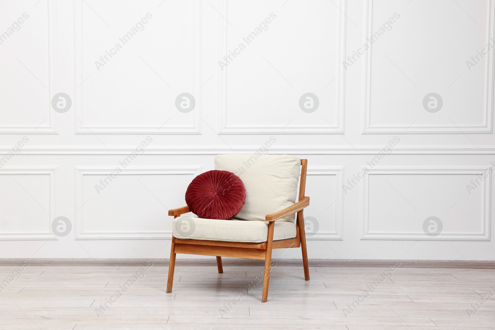 Photo of Comfortable soft armchair with pillow near white wall