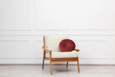 Photo of Comfortable soft armchair with pillow near white wall