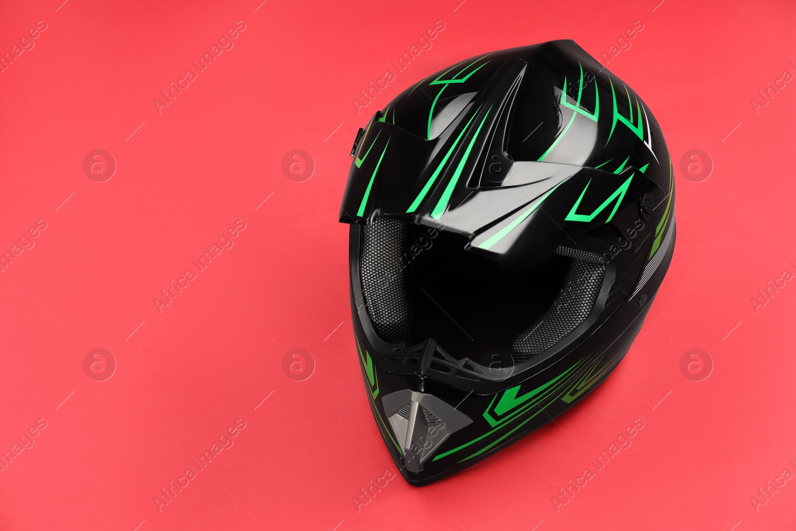 Photo of Modern motorcycle helmet with visor on red background. Space for text