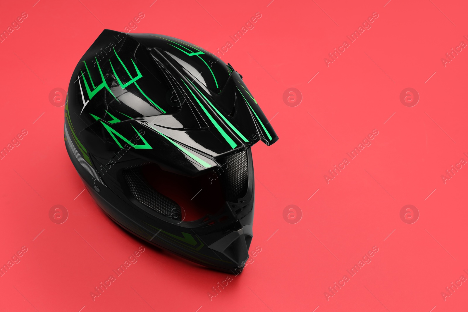 Photo of Modern motorcycle helmet with visor on red background. Space for text