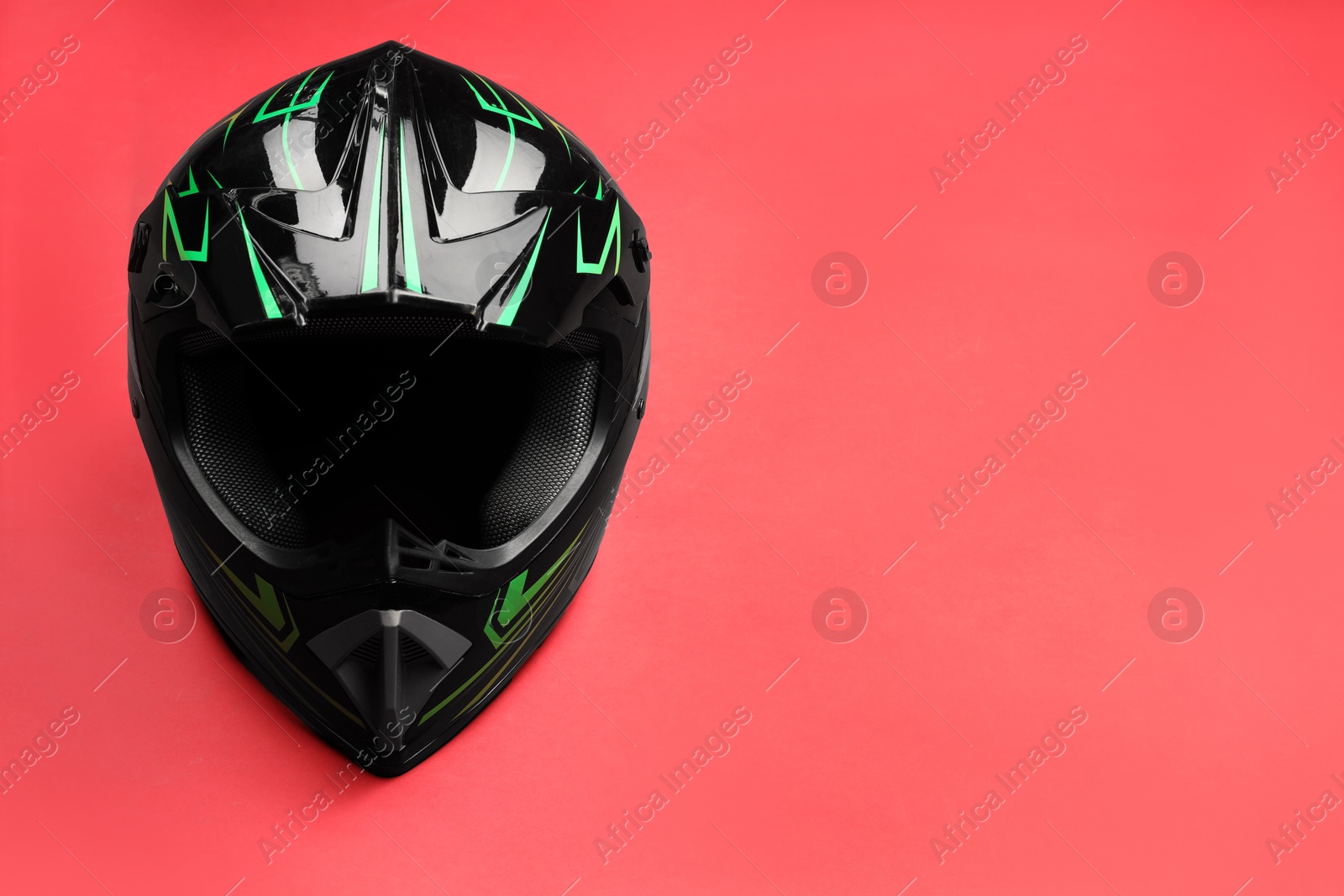 Photo of Modern motorcycle helmet with visor on red background. Space for text