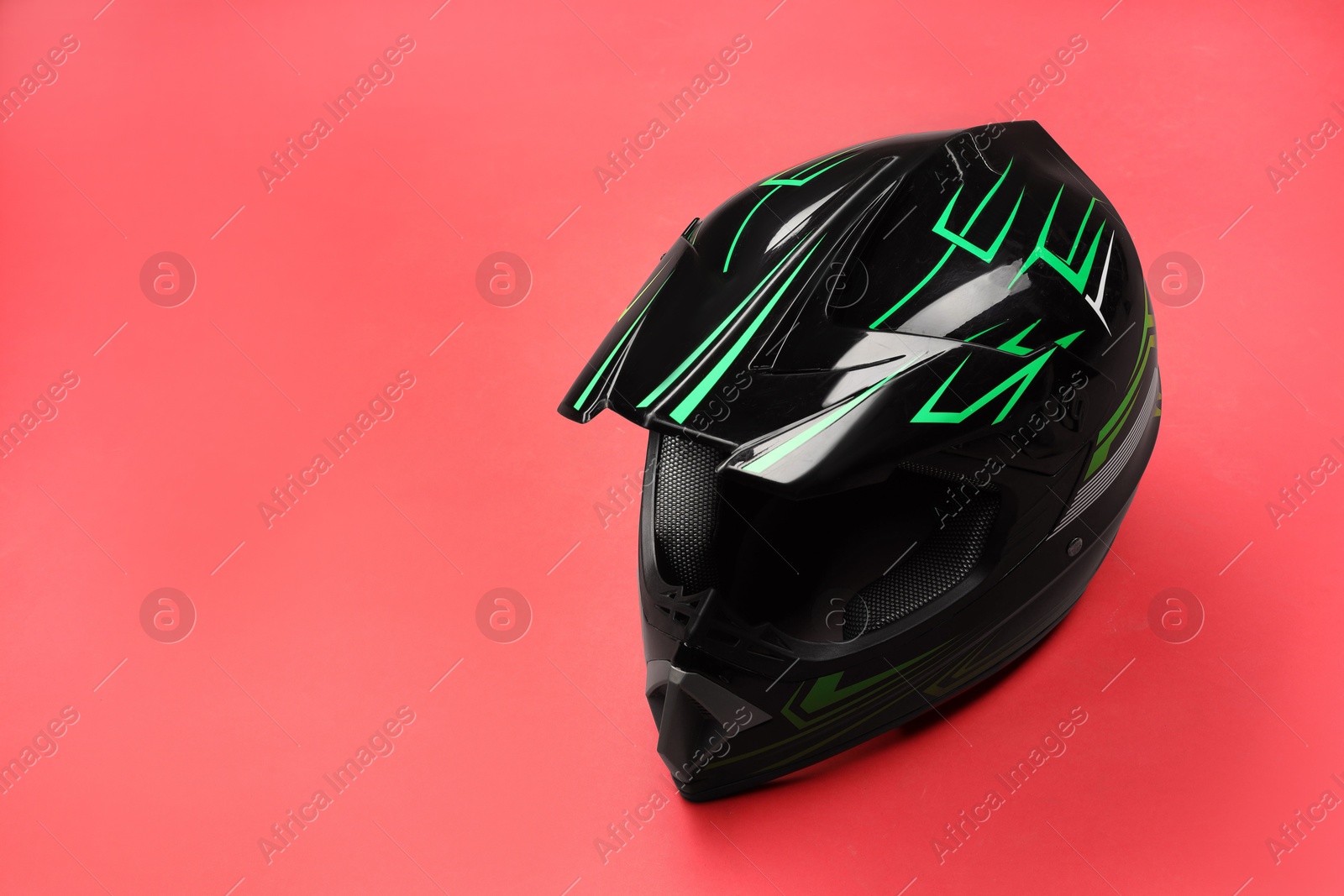 Photo of Modern motorcycle helmet with visor on red background. Space for text