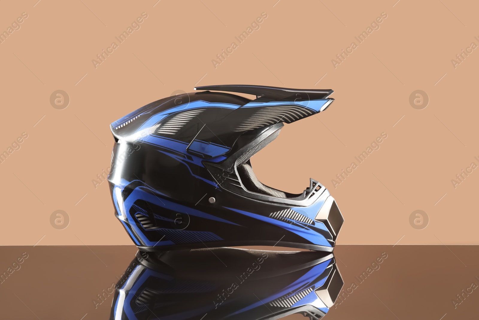 Photo of Modern motorcycle helmet with visor on mirror surface against beige background