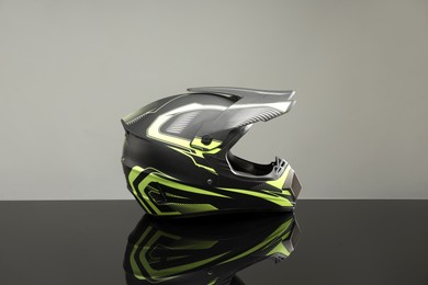 Modern motorcycle helmet with visor on mirror surface against light grey background