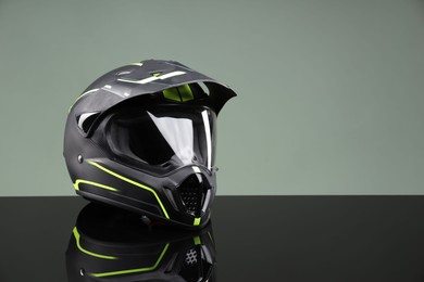 Modern motorcycle helmet with visor on mirror surface against light grey background. Space for text