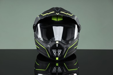 Modern motorcycle helmet with visor on mirror surface against light grey background