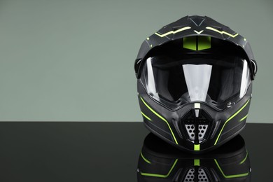 Modern motorcycle helmet with visor on mirror surface against light grey background. Space for text