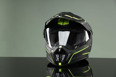 Modern motorcycle helmet with visor on mirror surface against light grey background. Space for text