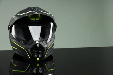 Photo of Modern motorcycle helmet with visor on mirror surface against light grey background. Space for text