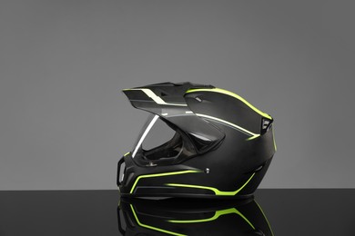 Modern motorcycle helmet with visor on mirror surface against light grey background. Space for text