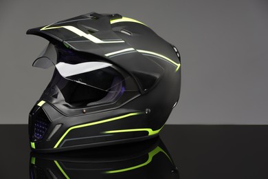 Modern motorcycle helmet with visor on mirror surface against light grey background. Space for text