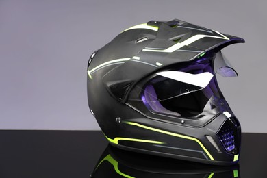 Modern motorcycle helmet with visor on mirror surface against light grey background. Space for text