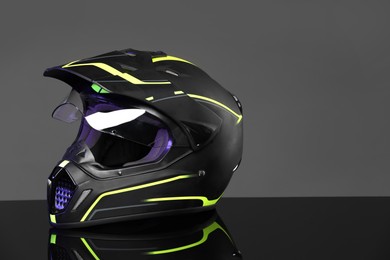 Photo of Modern motorcycle helmet with visor on mirror surface against light grey background. Space for text