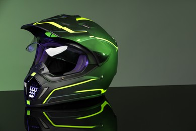 Modern motorcycle helmet with visor on mirror surface against light grey background. Space for text