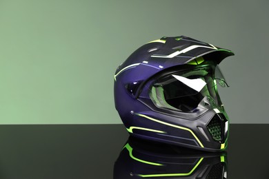 Modern motorcycle helmet with visor on mirror surface against grey background. Space for text