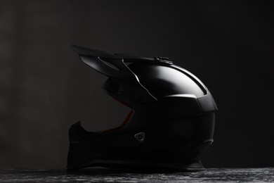 Modern motorcycle helmet with visor on grey stone surface against black background