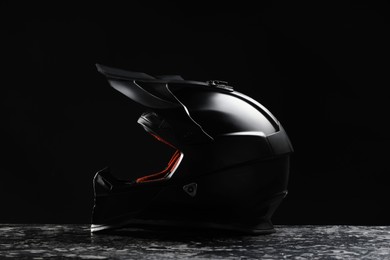 Modern motorcycle helmet with visor on grey stone surface against black background