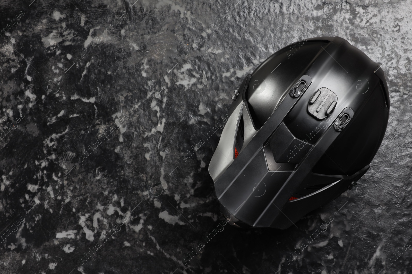 Photo of Modern motorcycle helmet with visor on grey stone surface, top view. Space for text