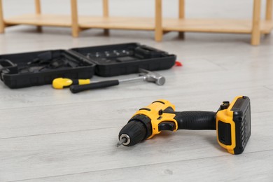 Electric screwdriver and other tools on floor in room