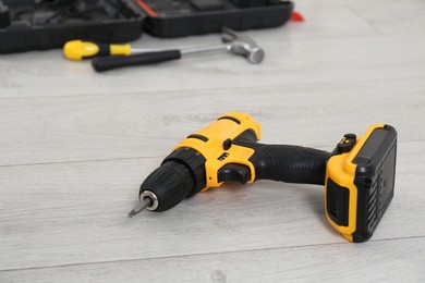 Photo of Cordless electric screwdriver and other tools on floor in room