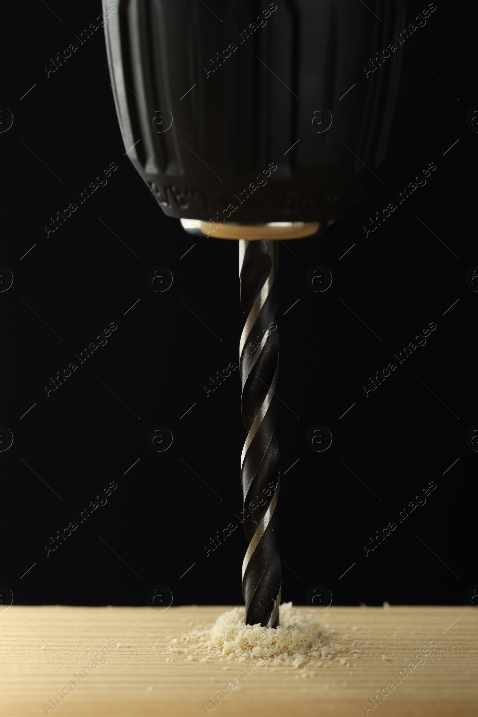 Photo of Drilling hole in wooden plank on black background, closeup