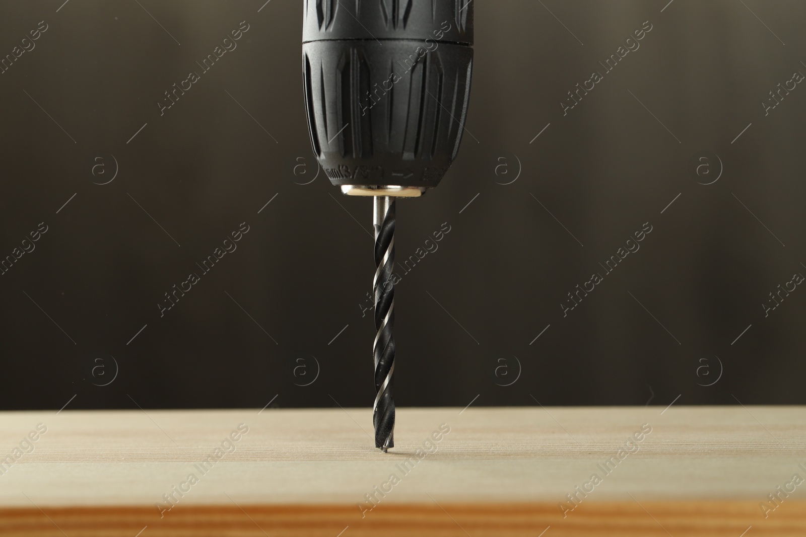 Photo of Drilling hole in wooden plank on grey background, closeup