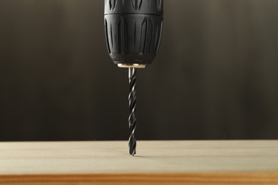 Photo of Drilling hole in wooden plank on grey background, closeup