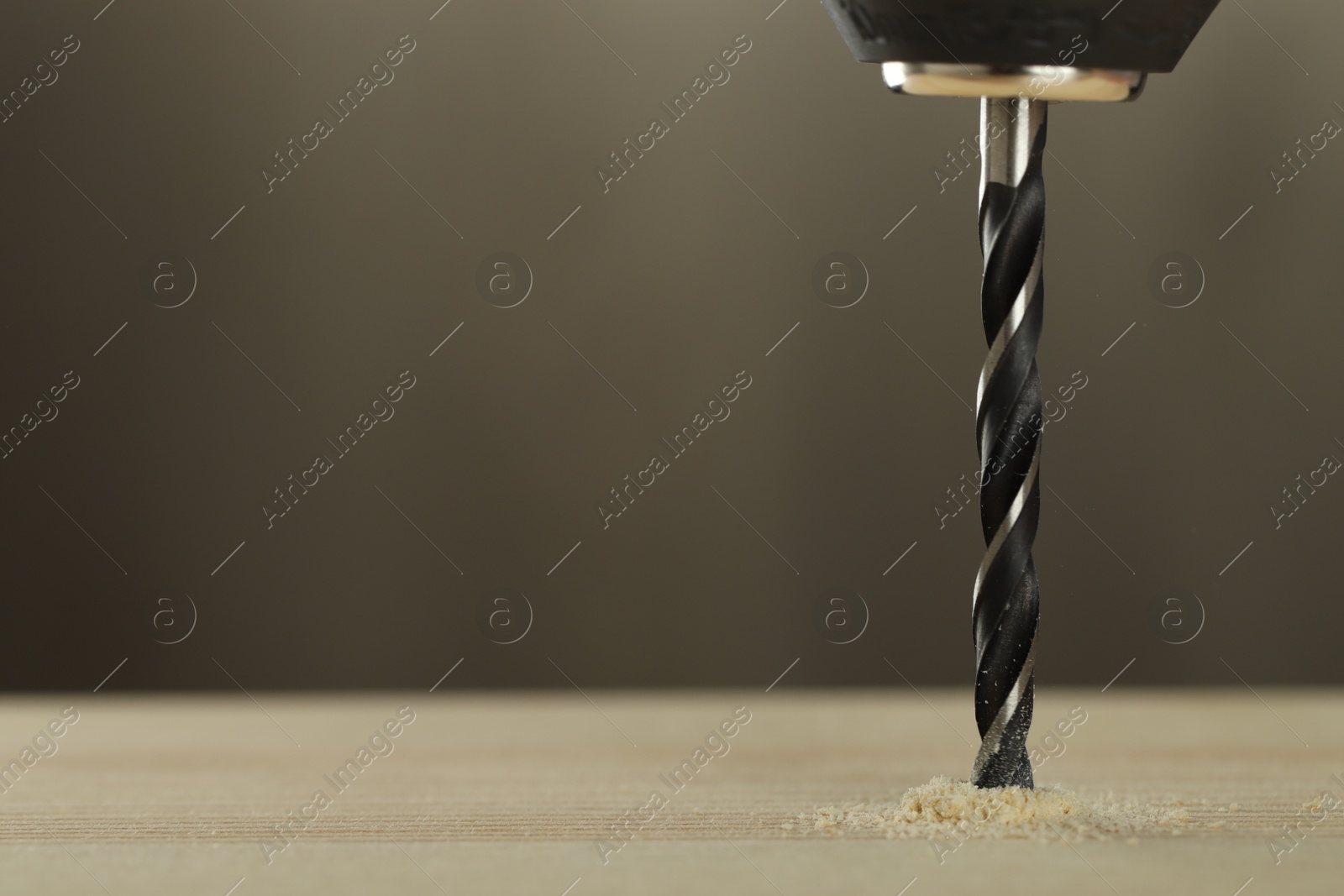 Photo of Drilling hole in wooden plank on grey background, closeup. Space for text