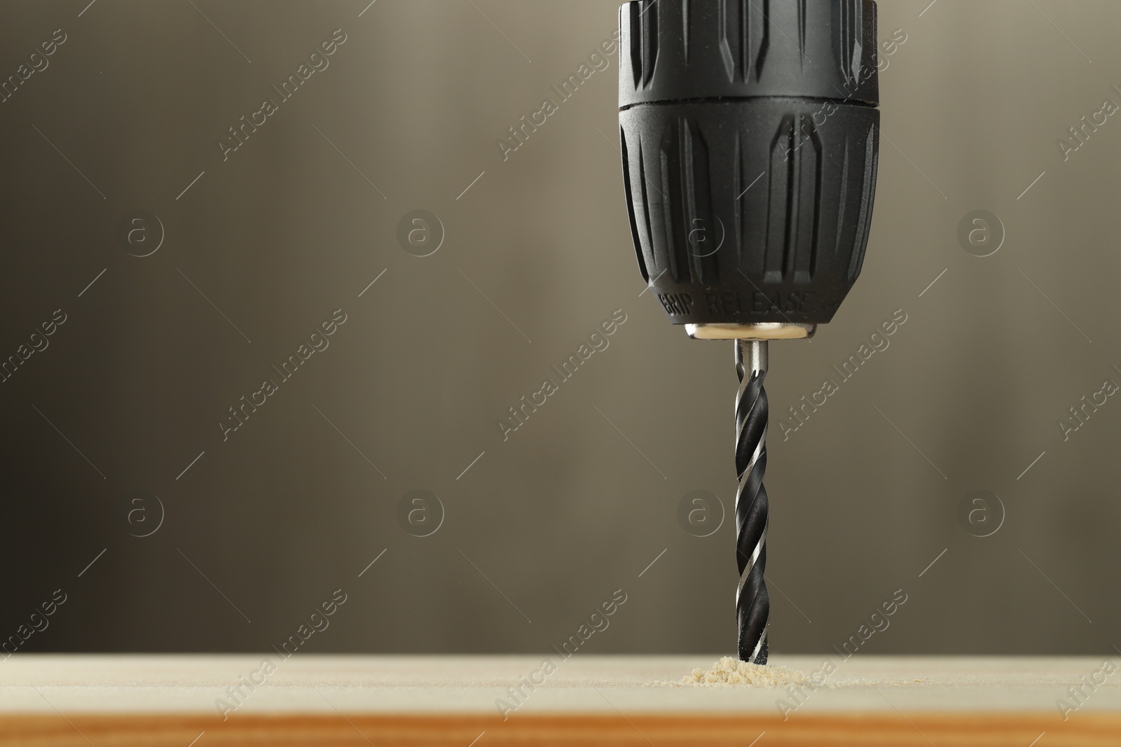 Photo of Drilling hole in wooden plank on grey background, closeup. Space for text