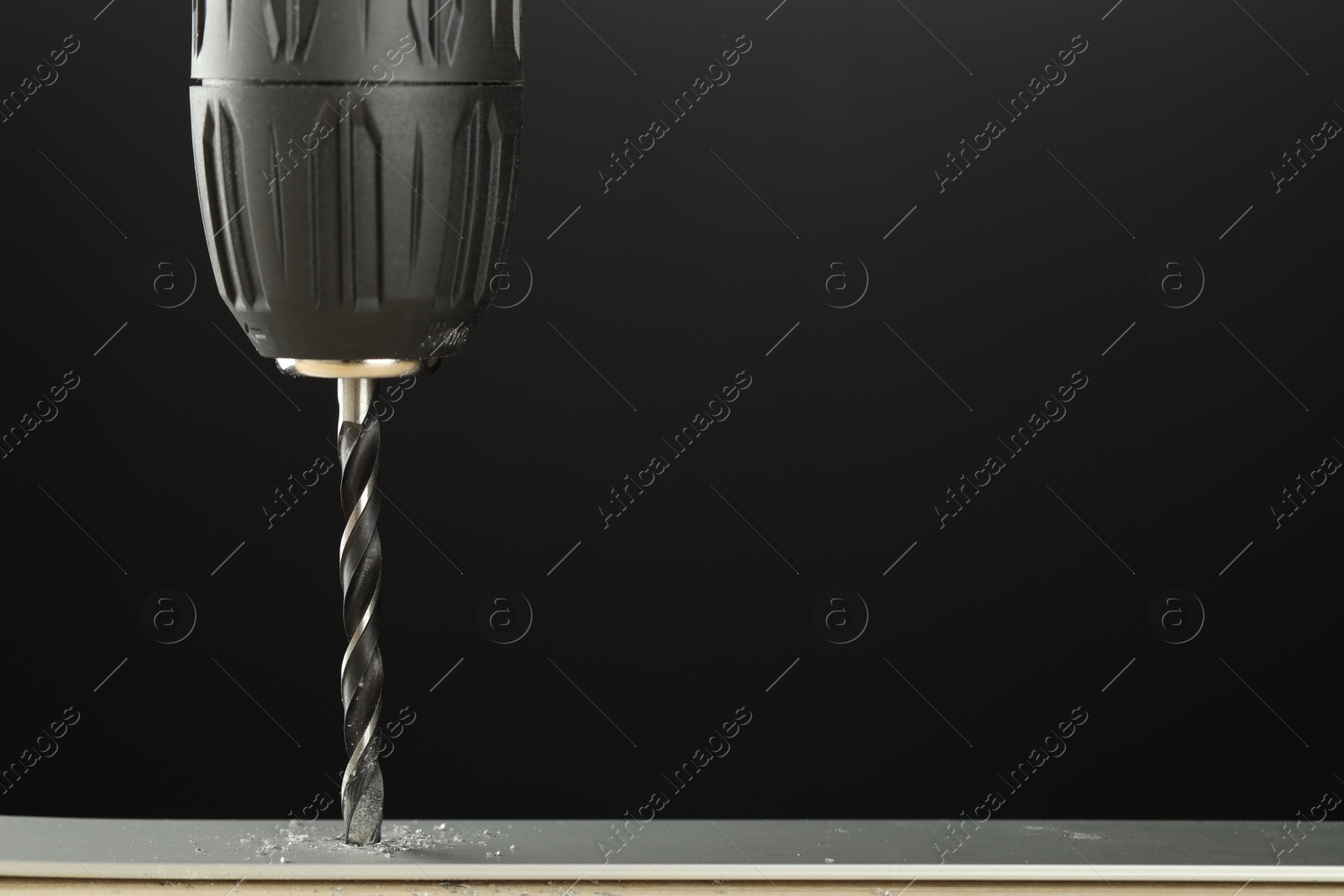 Photo of Drilling hole in grey surface on black background, closeup. Space for text