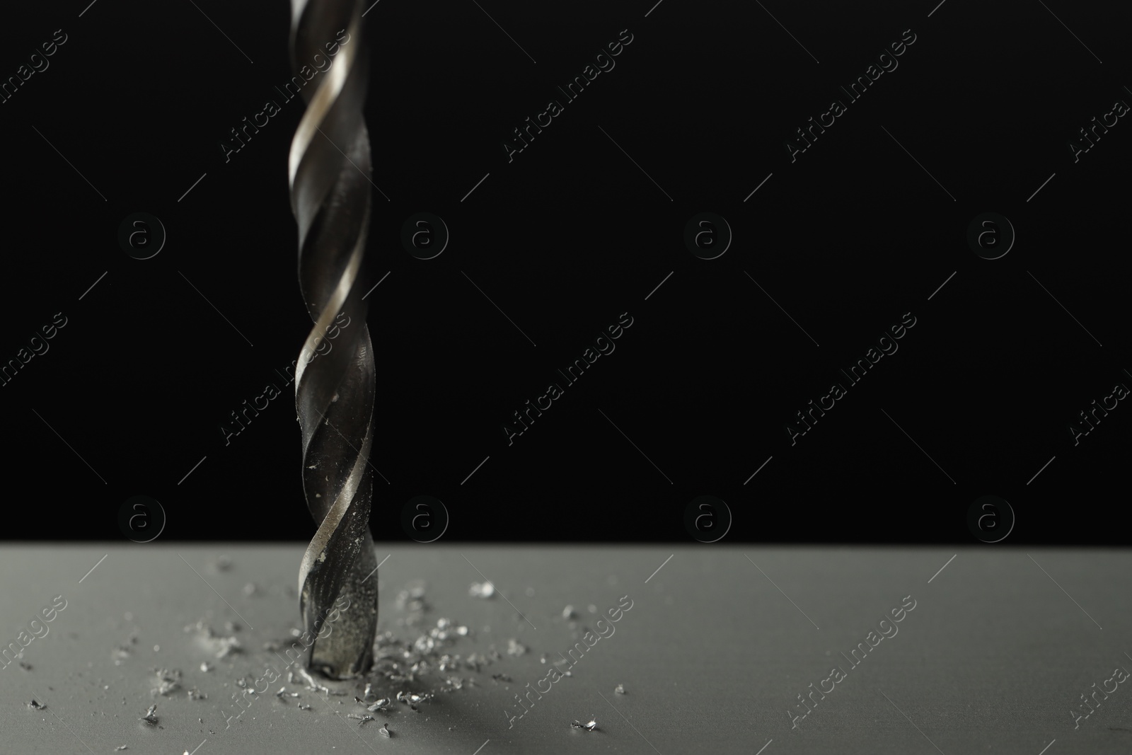 Photo of Drilling hole in grey surface on black background, closeup. Space for text