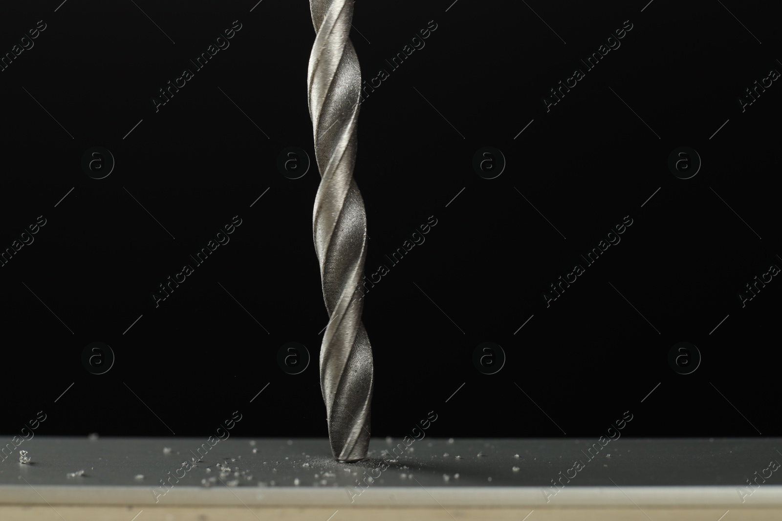 Photo of Drilling hole in grey surface on black background, closeup. Space for text