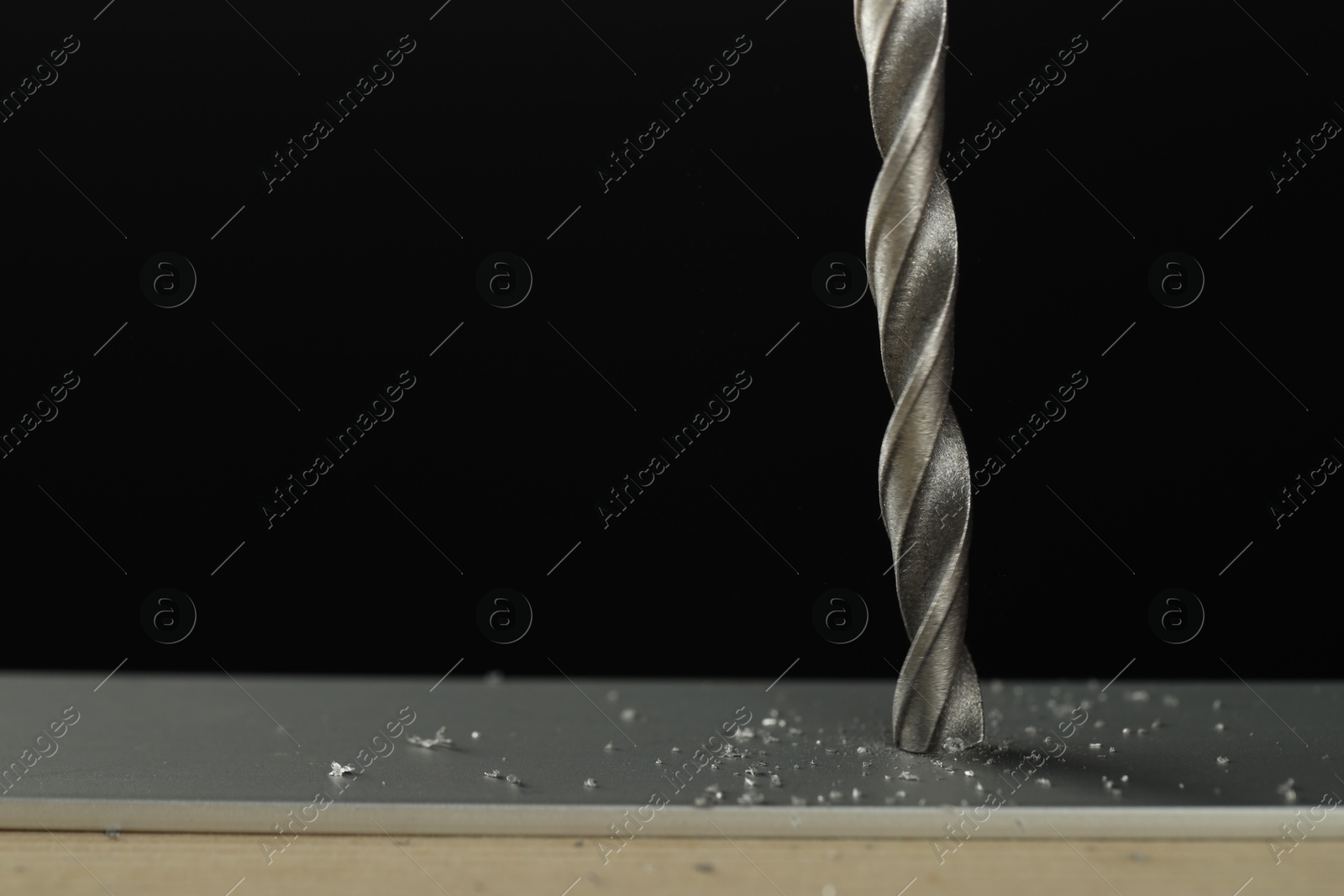 Photo of Drilling hole in grey surface on black background, closeup. Space for text