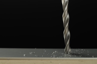 Photo of Drilling hole in grey surface on black background, closeup. Space for text