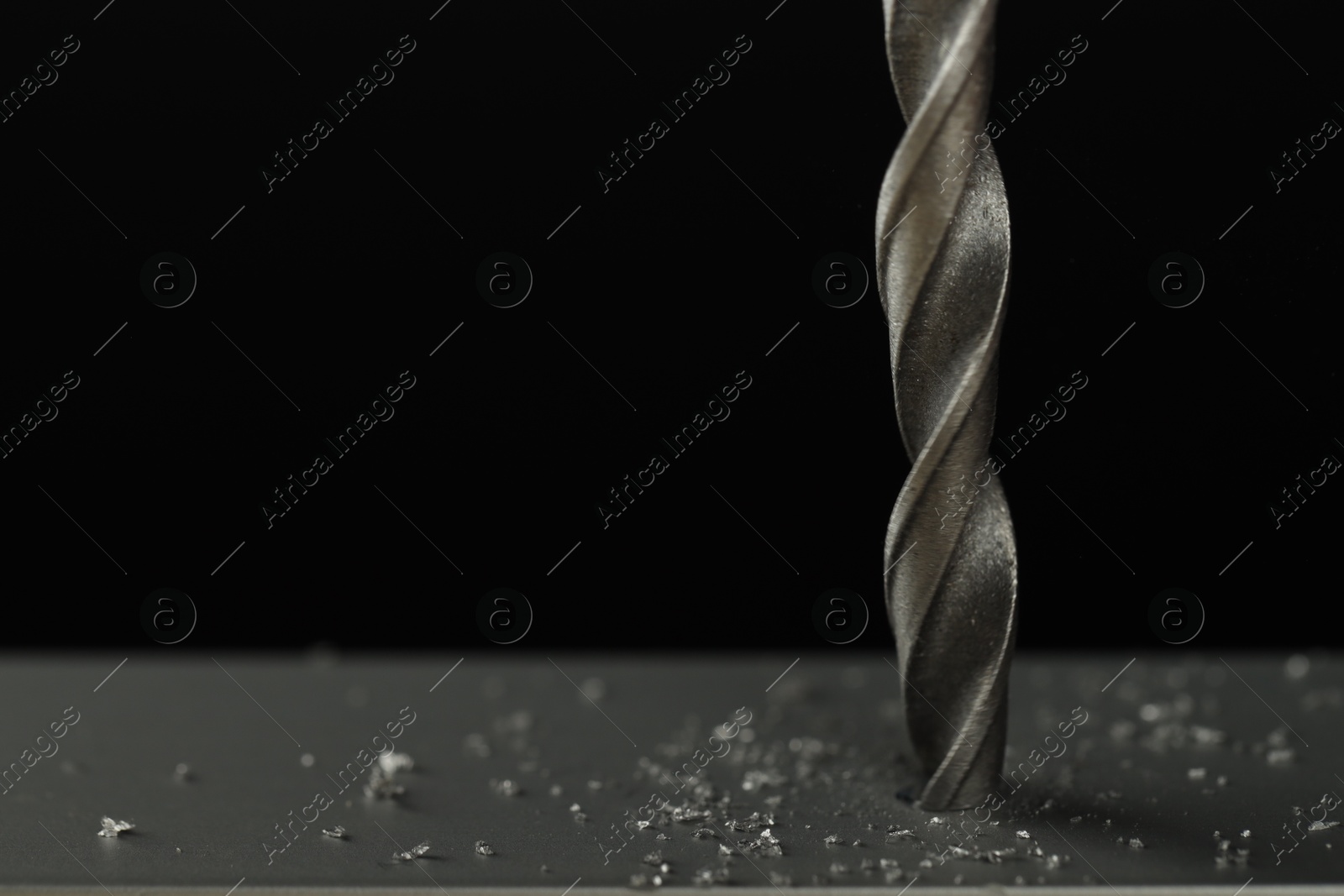 Photo of Drilling hole in grey surface on black background, closeup. Space for text