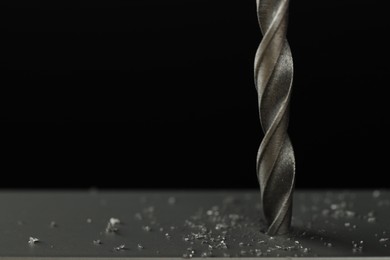 Photo of Drilling hole in grey surface on black background, closeup. Space for text