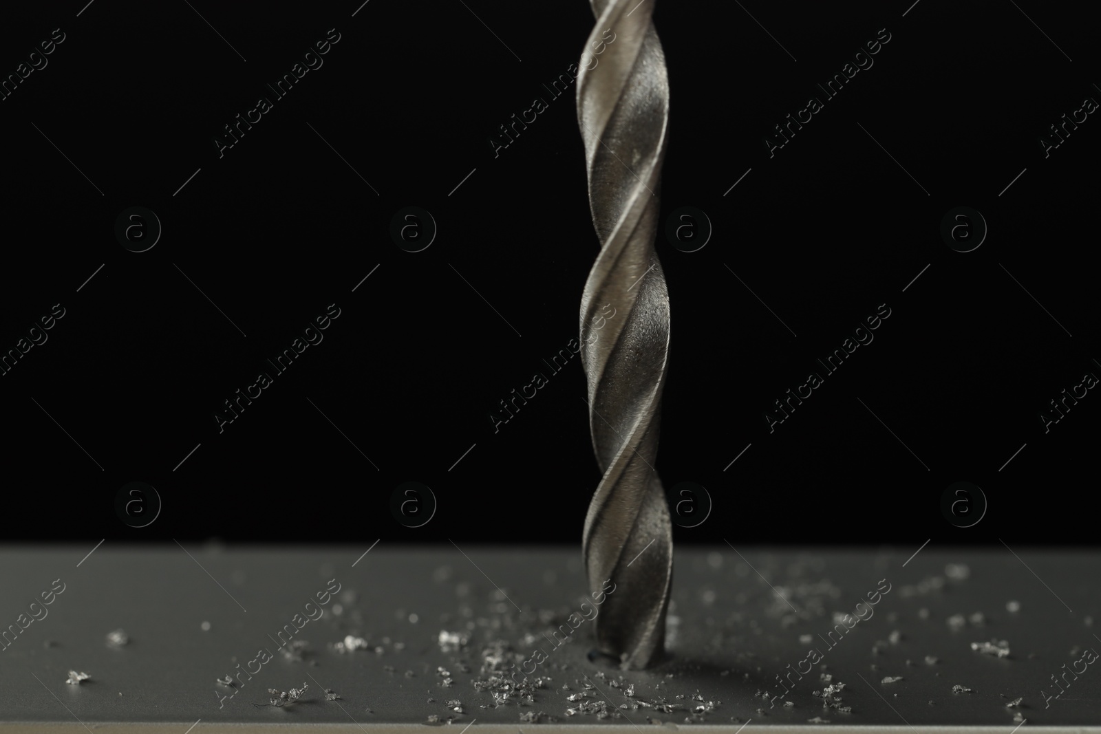 Photo of Drilling hole in grey surface on black background, closeup