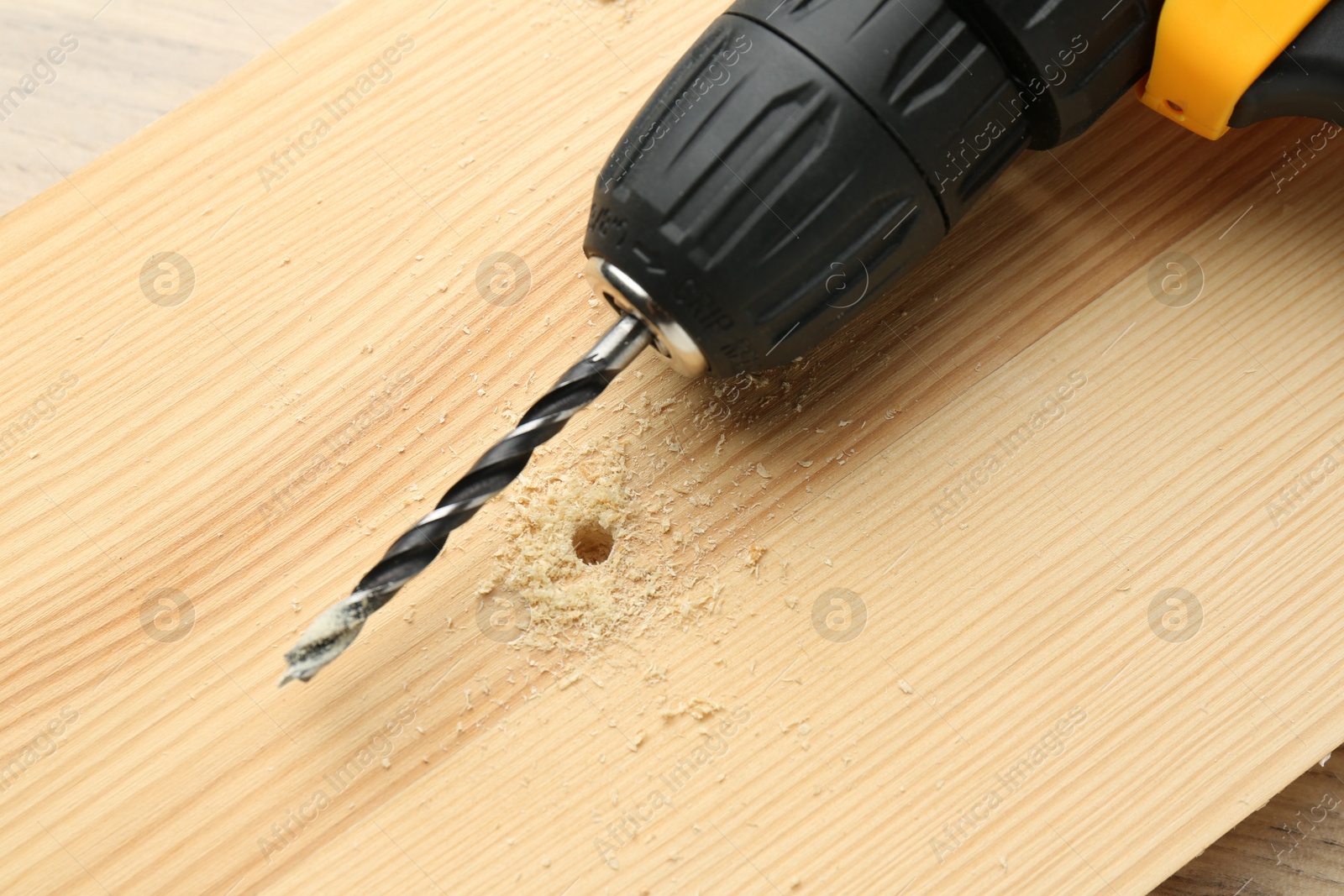 Photo of Cordless electric drill on holed wooden surface