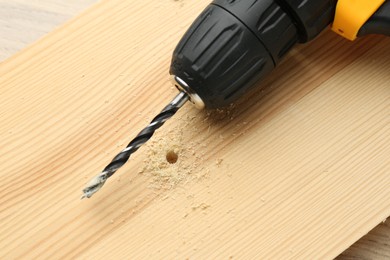 Photo of Cordless electric drill on holed wooden surface