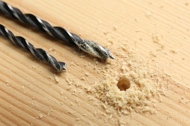 Photo of Drill bits and sawdust on holed wooden surface, closeup