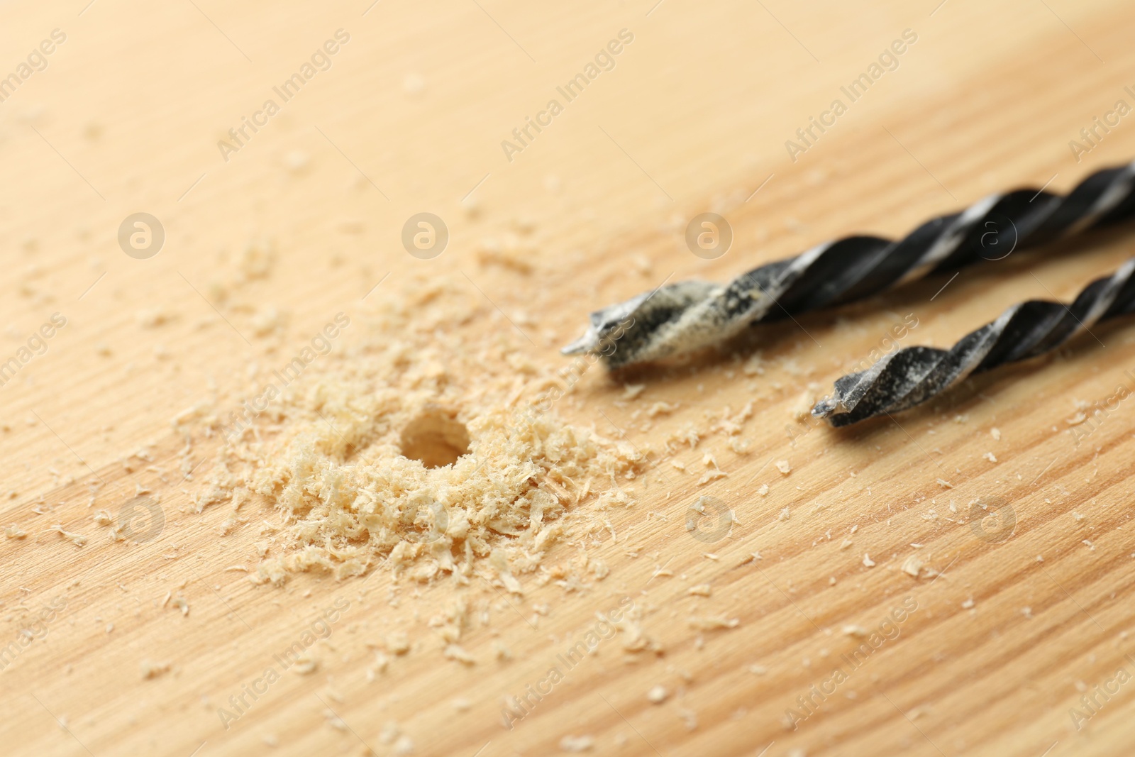 Photo of Drill bits and sawdust on holed wooden surface, closeup