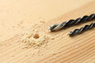 Drill bits and sawdust on holed wooden surface, closeup