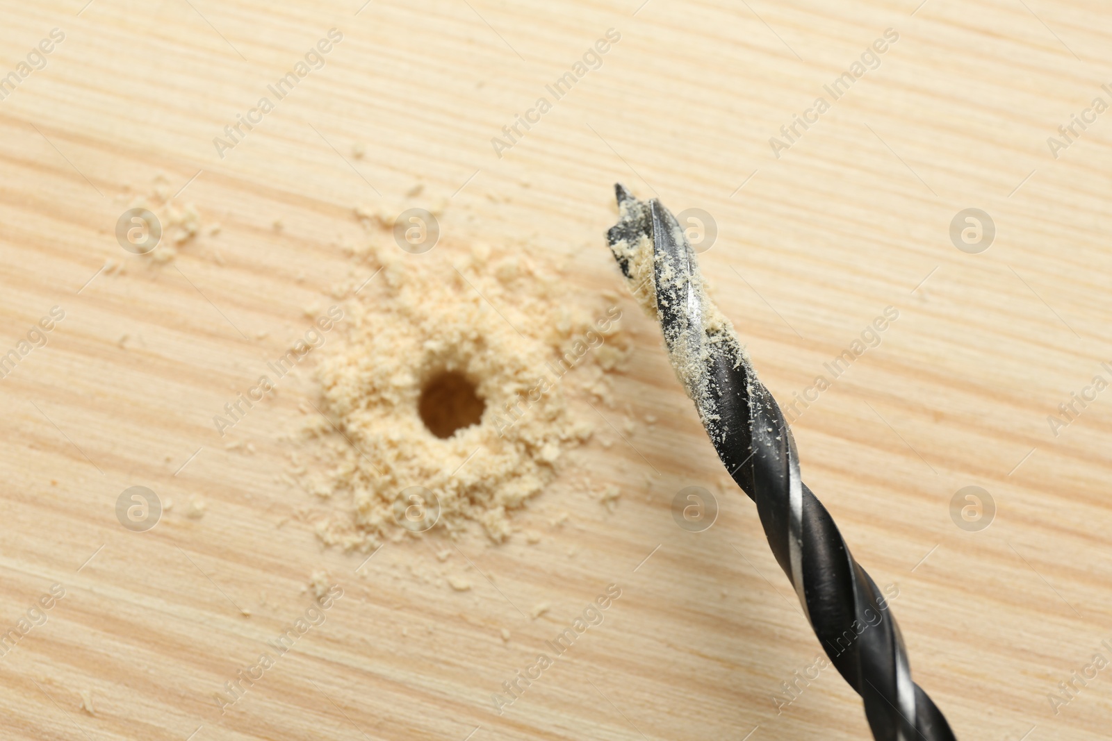 Photo of Drill bit and sawdust on holed wooden surface, closeup