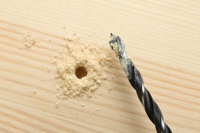 Photo of Drill bit and sawdust on holed wooden surface, closeup